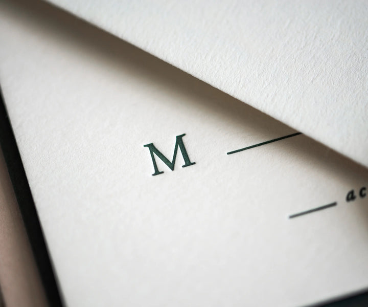 Green M letter letterpress printed on white paper