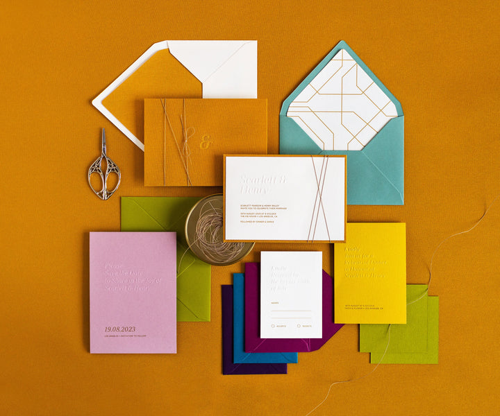 Top view of colourful letterpress wedding invitation set and envelopes