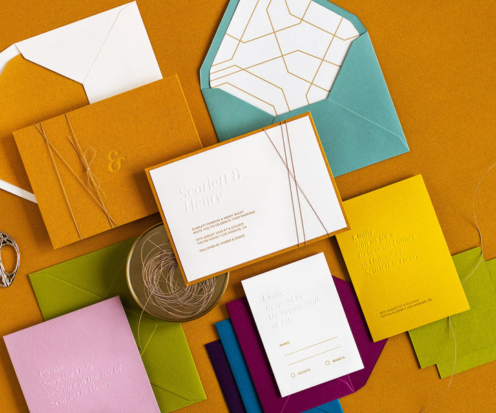 Angled top view of colourful letterpress wedding invitation set and envelopes