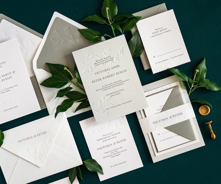 Angled top view of ivy themed letterpress wedding invitation set and envelopes