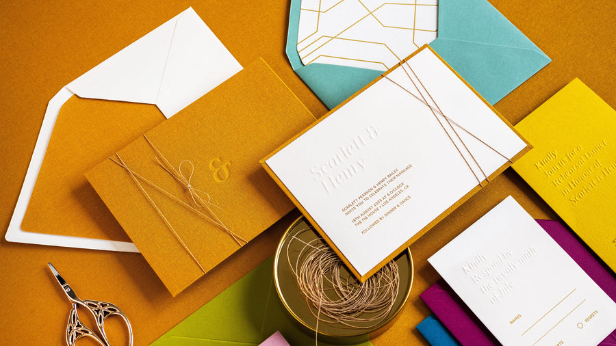 Flatlay of letterpress invitations and coloured handmade envelopes