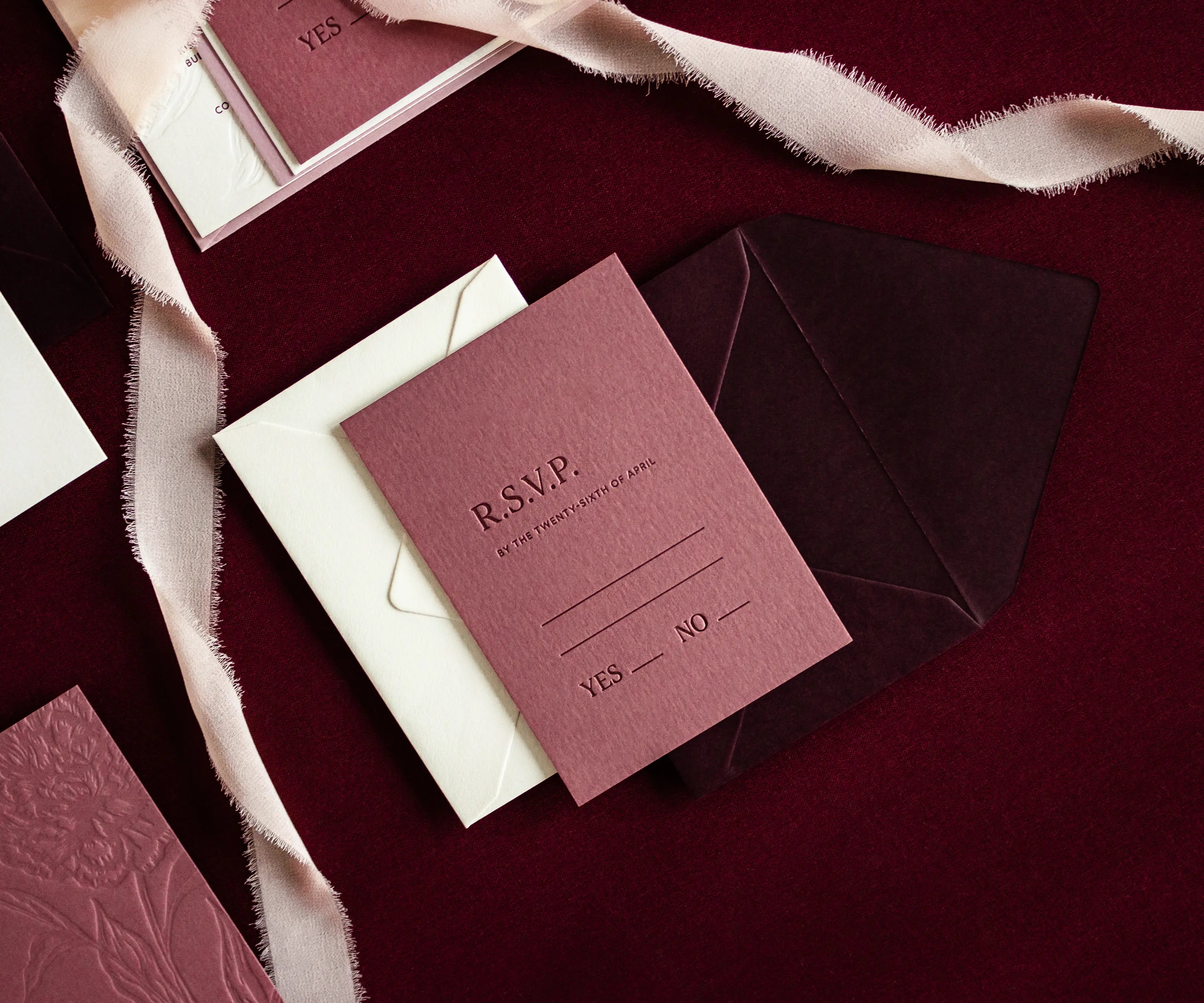 Letterpress RSVP card on envelope next to silk ribbon