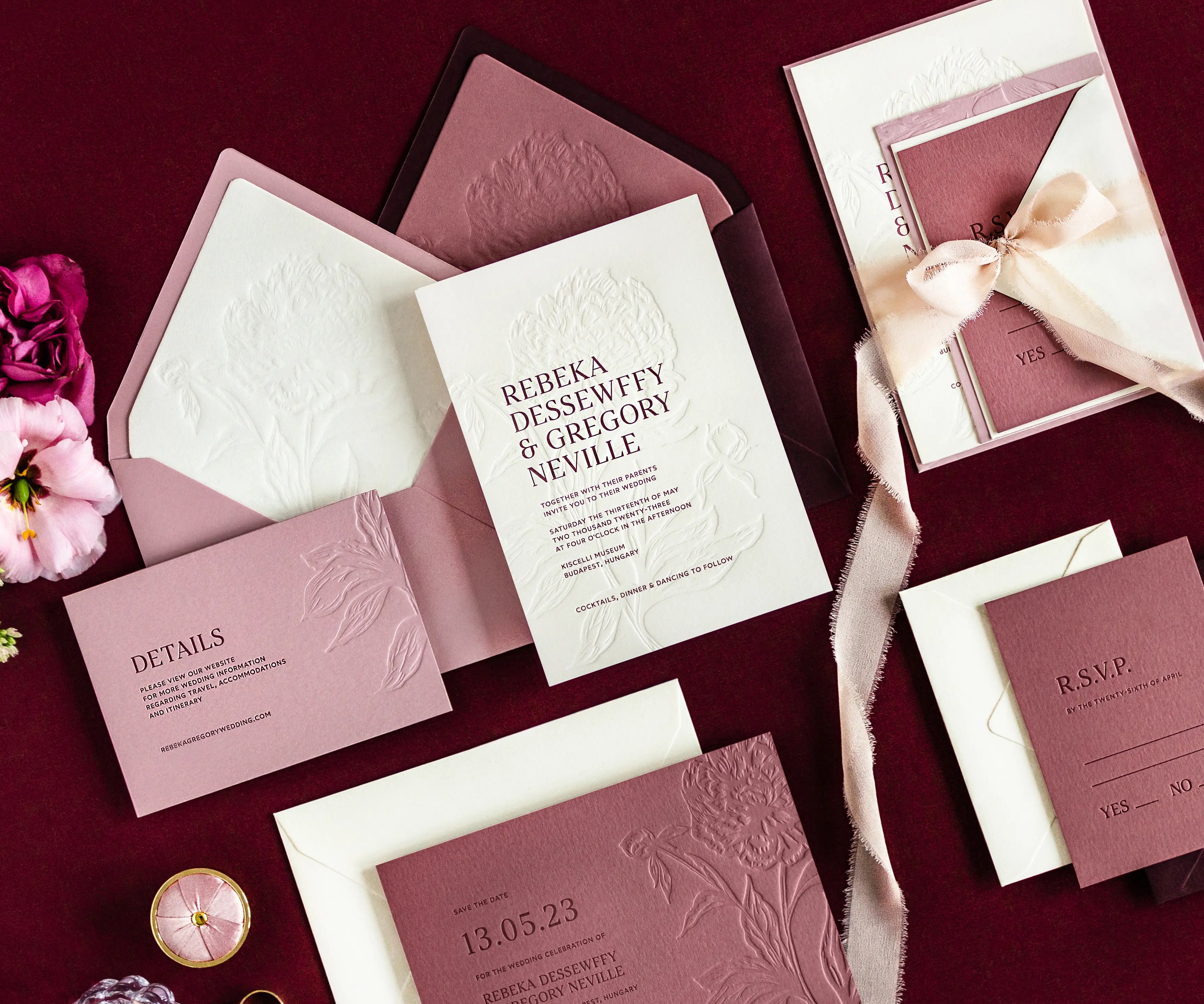 Angled top view of peony themed letterpress wedding invitation set and envelopes