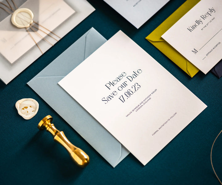 Letterpress Save the Date card next to brass stamper and wax seal
